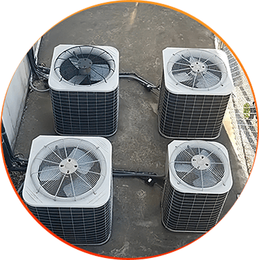 Four outdoor HVAC units on a concrete surface next to a building.