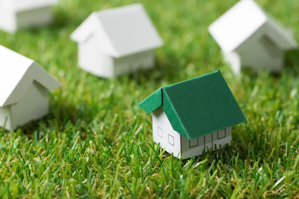 Stay Green: Eco-friendly Air Conditioning Options for the Modern Home - Paper craft of houses on a lawn. All are white papper, one has a green roof.