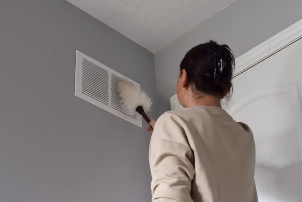 The Connection Between Efficient Heating and Clean Ducts in Searcy Homes - Woman cleaning air vents at home