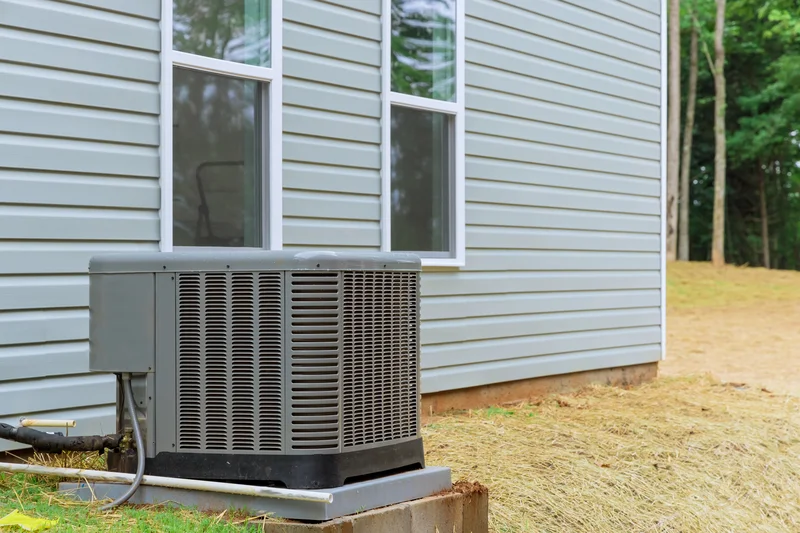Outdoor HVAC unit next to a house with light gray siding.