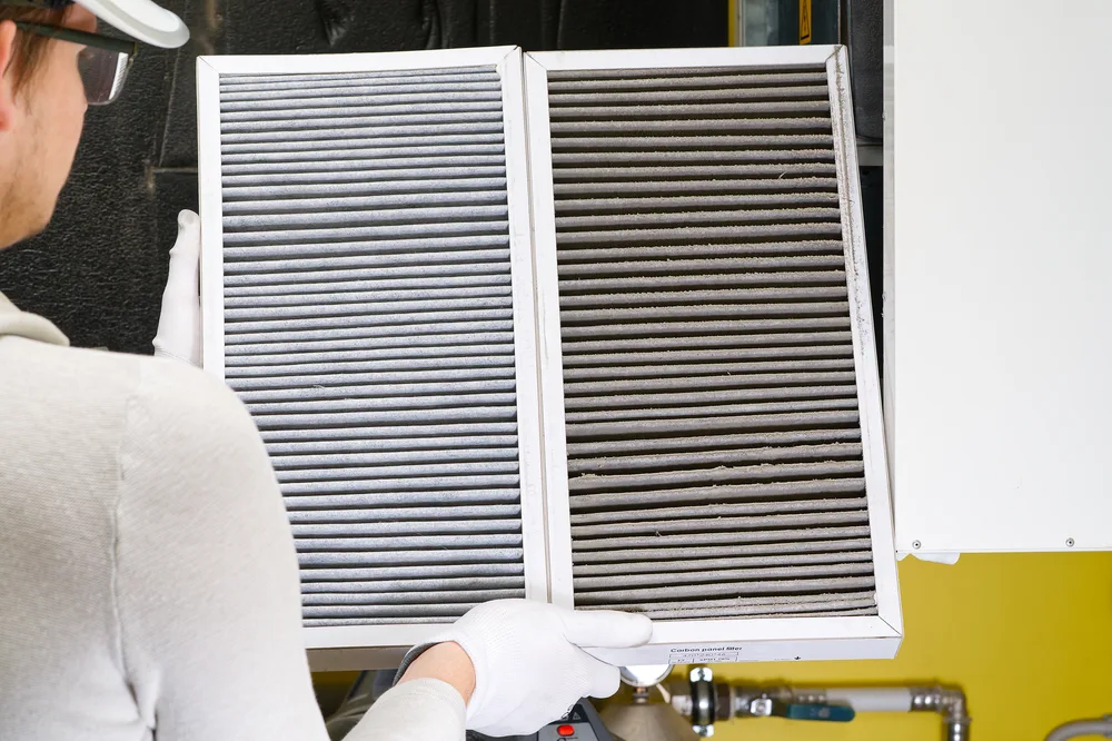 Technician holding a clean and a dirty air filter side by side.
