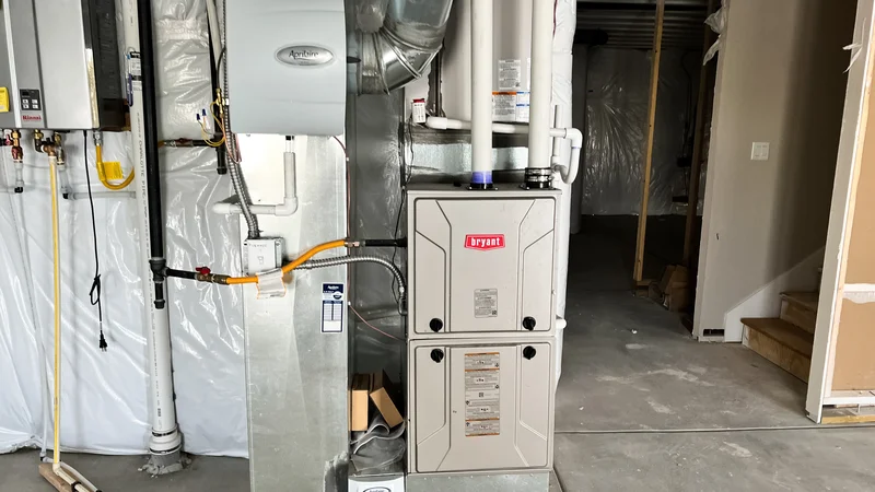 HVAC system installed in a basement with ductwork and a Bryant furnace alongside other heating equipment.