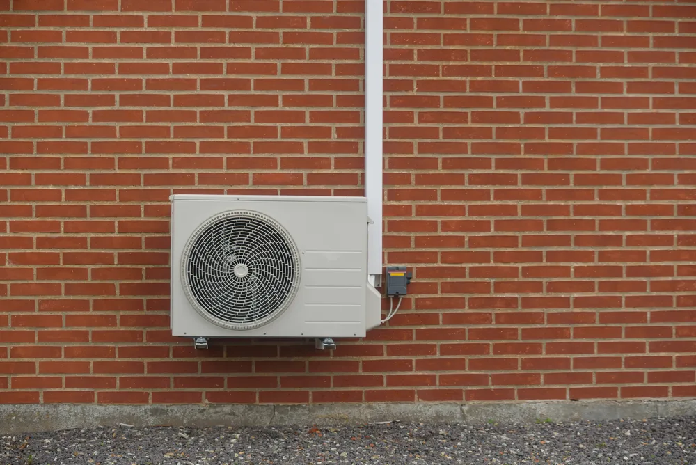 Outdoor HVAC unit mounted on a red brick wall.